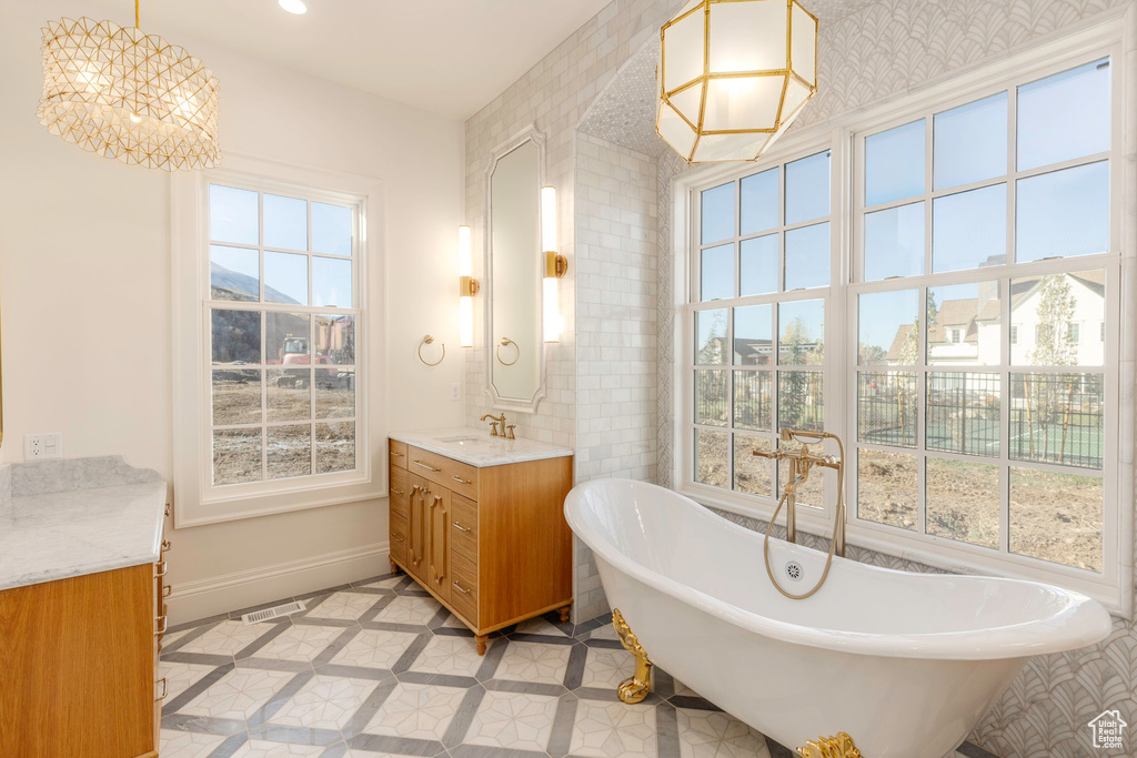 Bathroom with vanity, a washtub, and a wealth of natural light