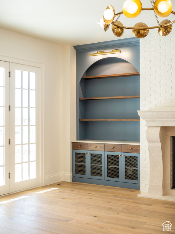 Unfurnished living room with built in shelves, a brick fireplace, and hardwood / wood-style flooring