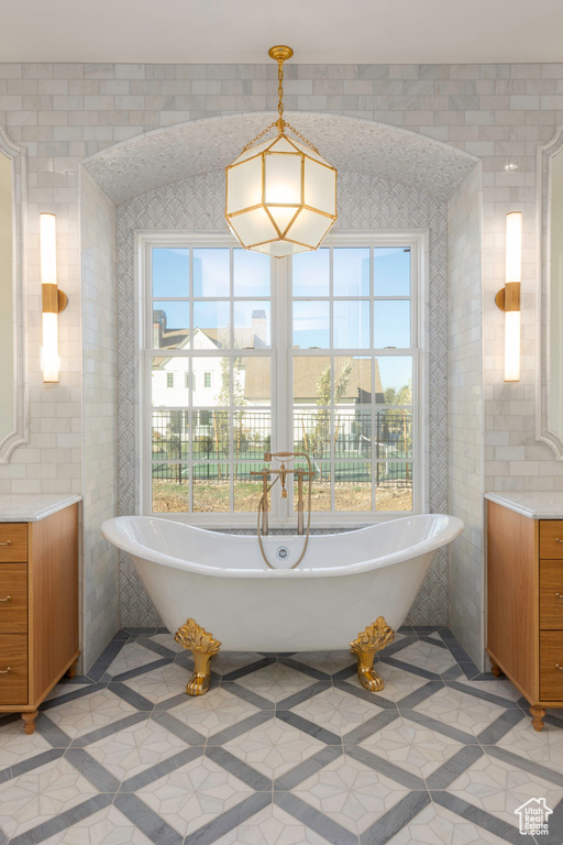 Bathroom with a wealth of natural light, a washtub, and tile walls