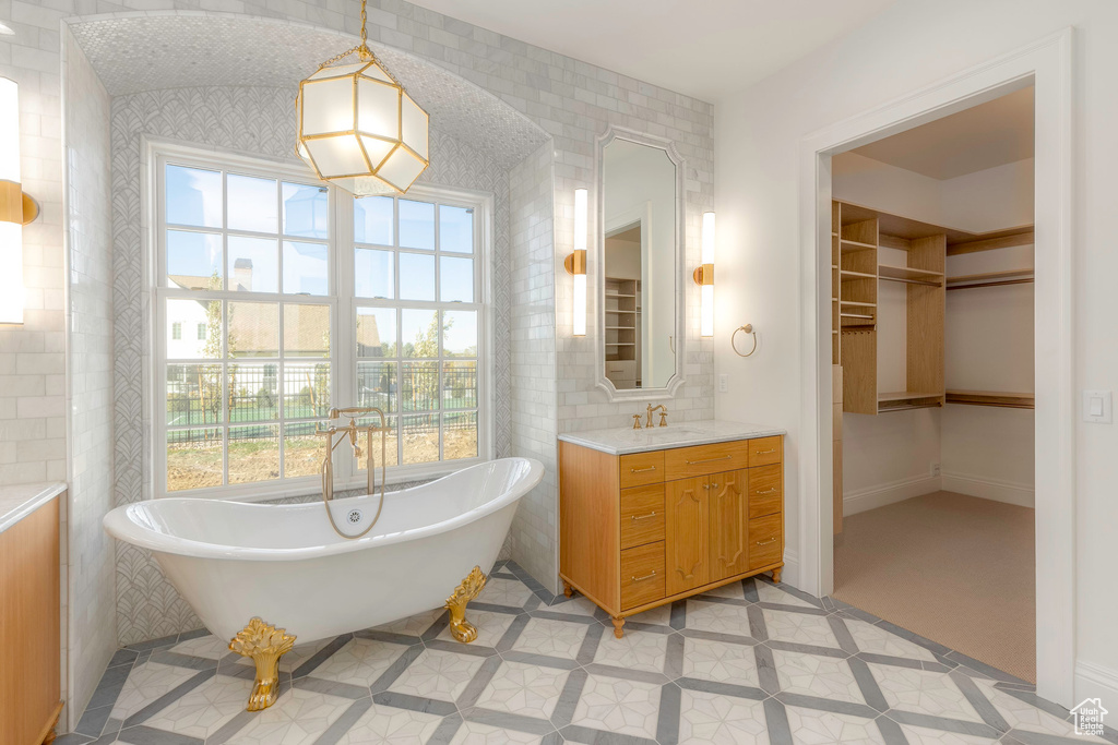 Bathroom with tile walls, a washtub, and vanity