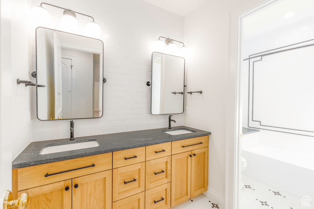 Bathroom featuring vanity, tile patterned floors, toilet, and backsplash