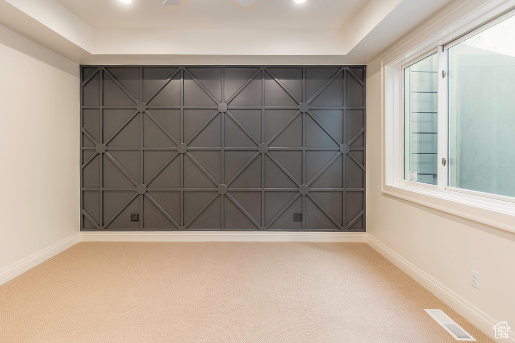 Carpeted spare room featuring a raised ceiling