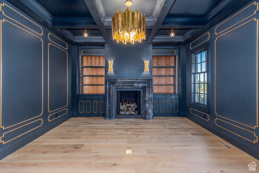 Unfurnished living room featuring beamed ceiling, wood-type flooring, crown molding, and coffered ceiling