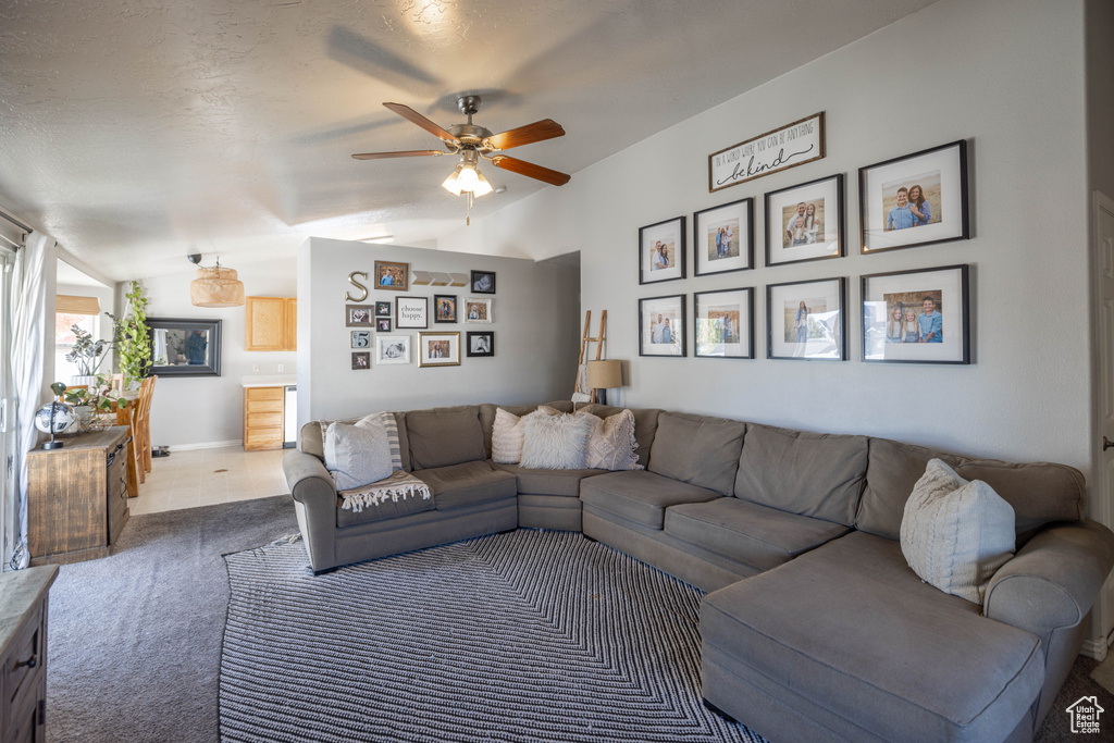 Carpeted living room with lofted ceiling, a textured ceiling, and ceiling fan