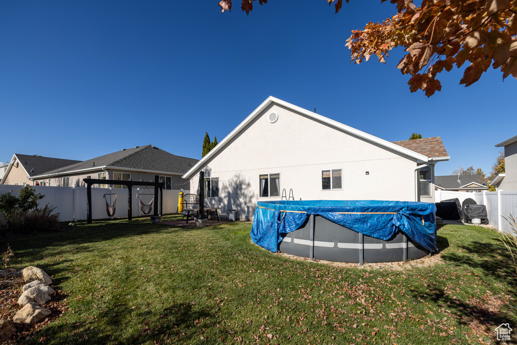 Back of house featuring a lawn and a covered pool