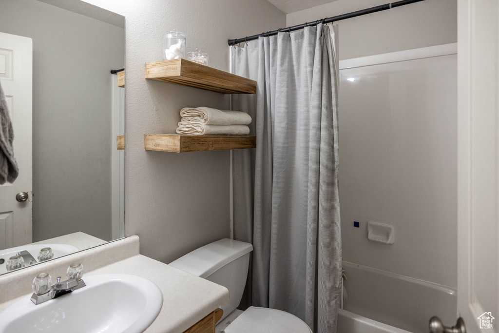 Full bathroom with vanity, toilet, and shower / bathtub combination with curtain