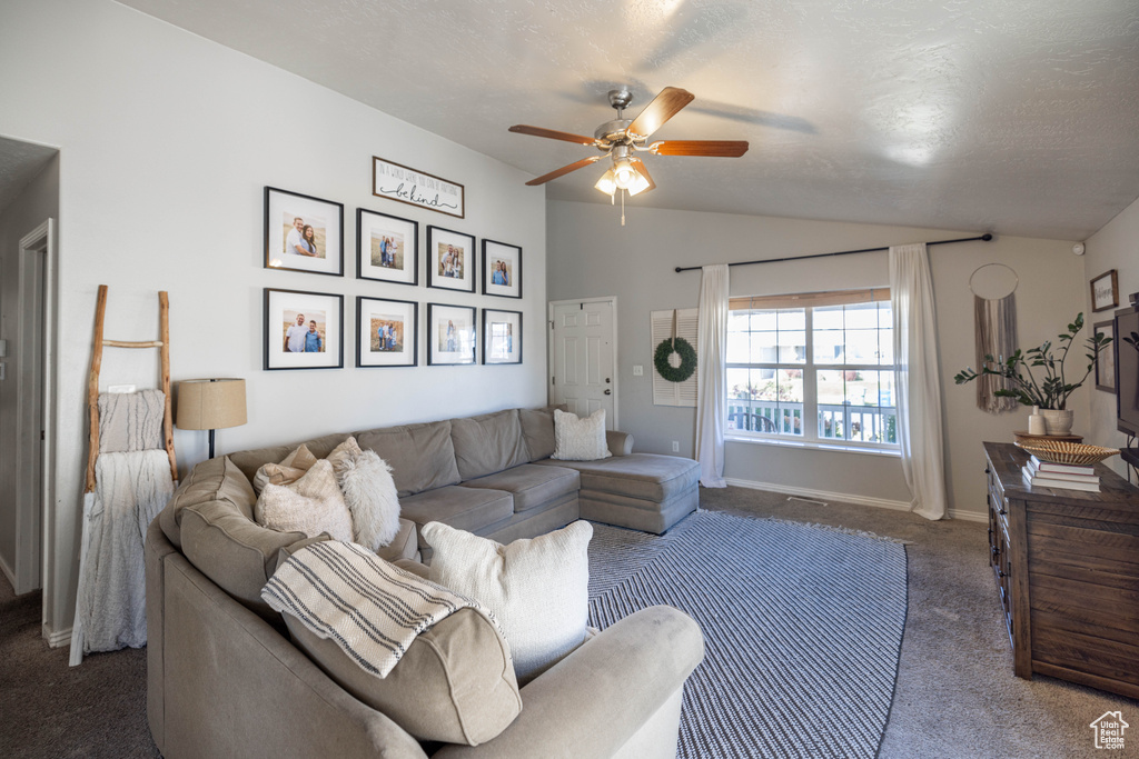 Living room with a textured ceiling, ceiling fan, vaulted ceiling, and dark carpet