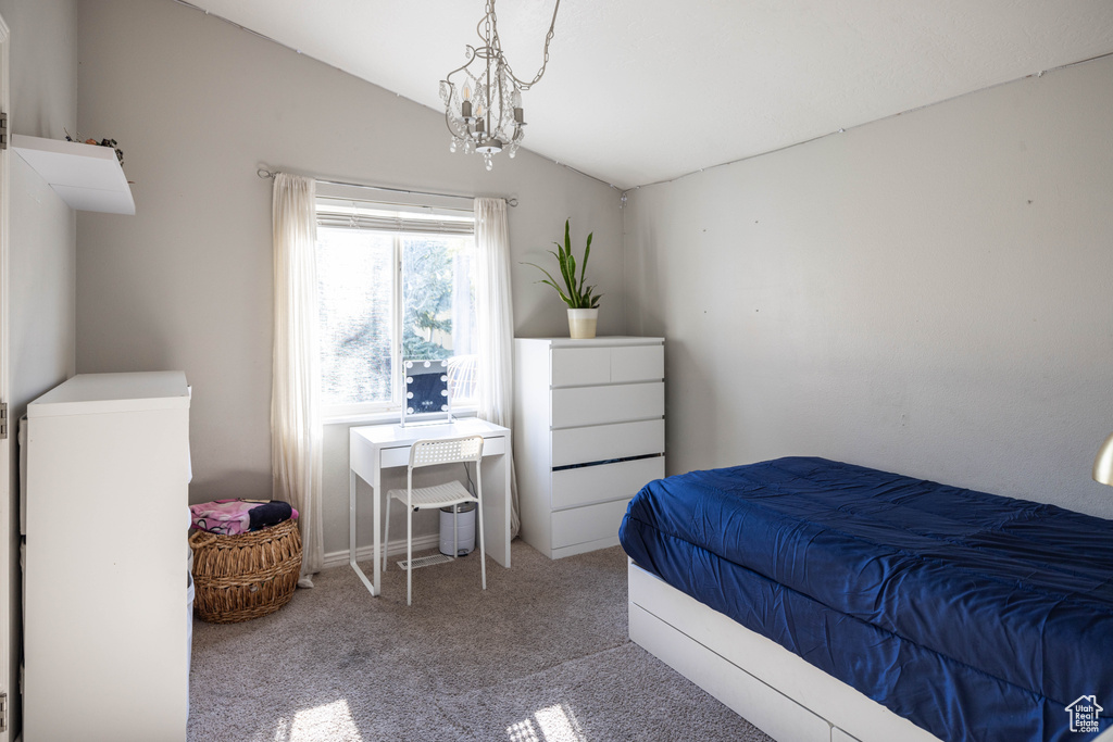 Carpeted bedroom with lofted ceiling and an inviting chandelier