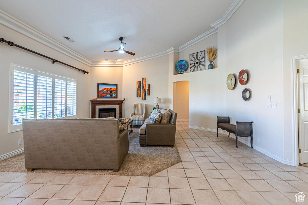 Living area with ceiling fan, crown molding, light tile patterned floors, a fireplace, and baseboards