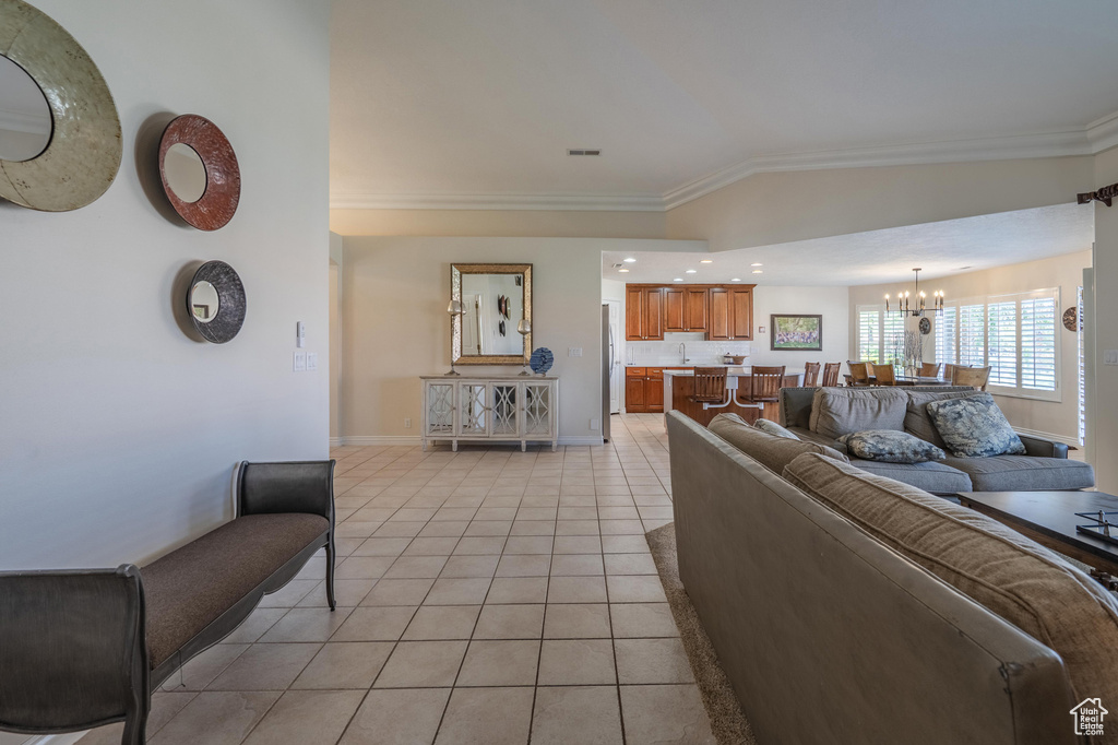 Living area with a chandelier, ornamental molding, light tile patterned floors, and baseboards