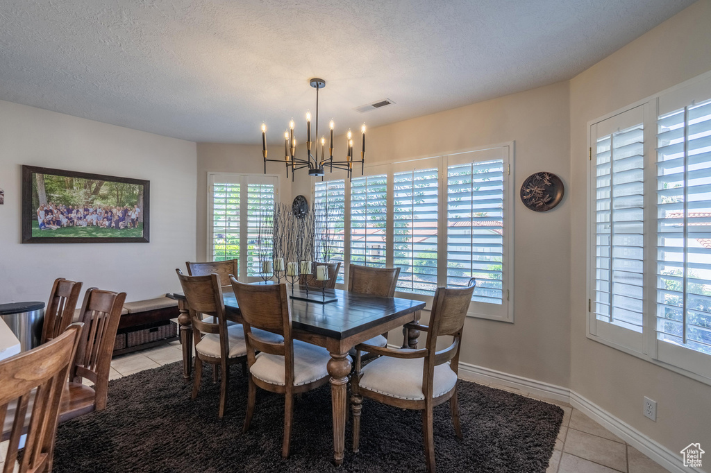 Dining area featuring a chandelier, light tile patterned floors, and baseboards