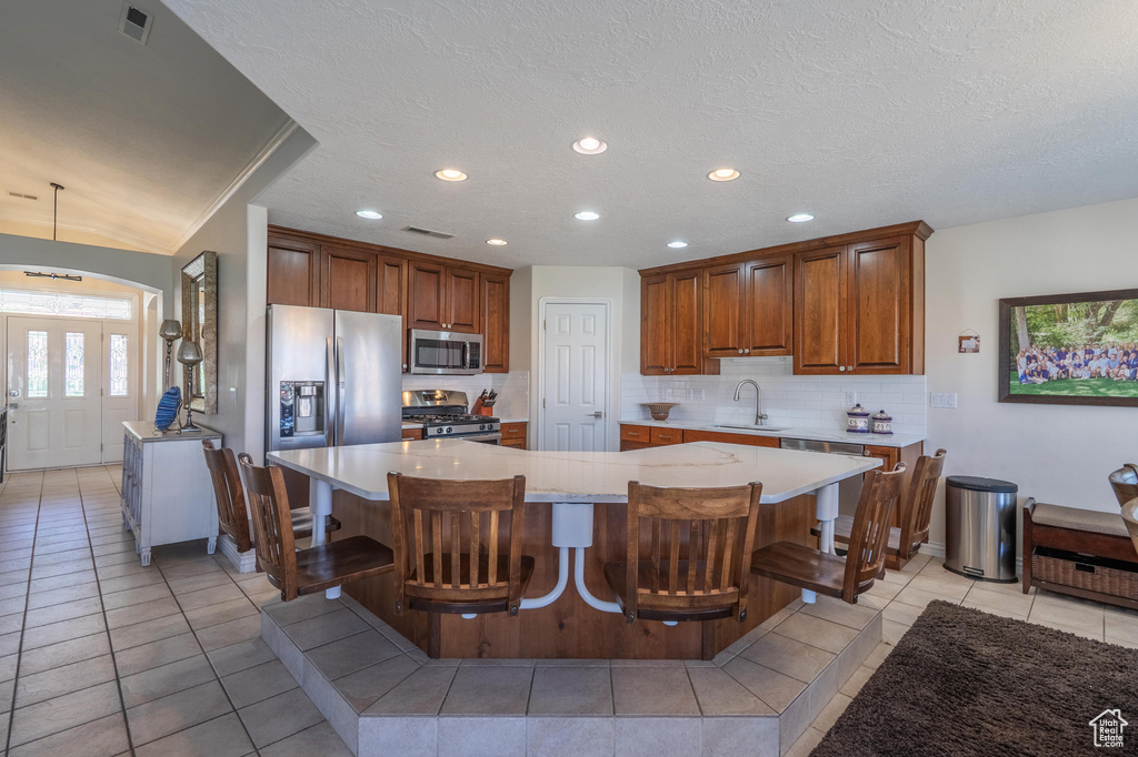 Kitchen featuring stainless steel appliances, tasteful backsplash, a spacious island, light countertops, and recessed lighting