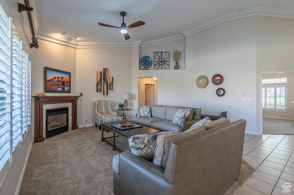 Living room with a ceiling fan, crown molding, a tiled fireplace, arched walkways, and baseboards