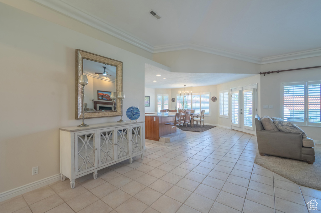 Living area with ornamental molding, light tile patterned floors, baseboards, plenty of natural light, and a chandelier