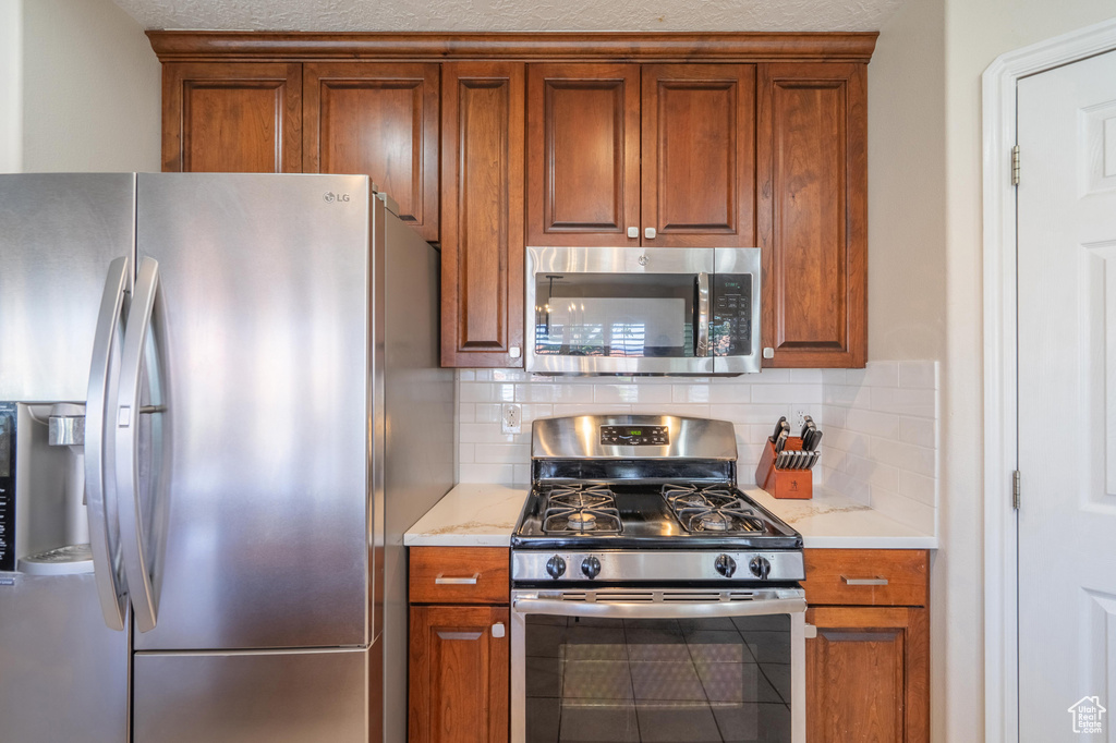 Kitchen with stainless steel appliances, backsplash, and brown cabinetry