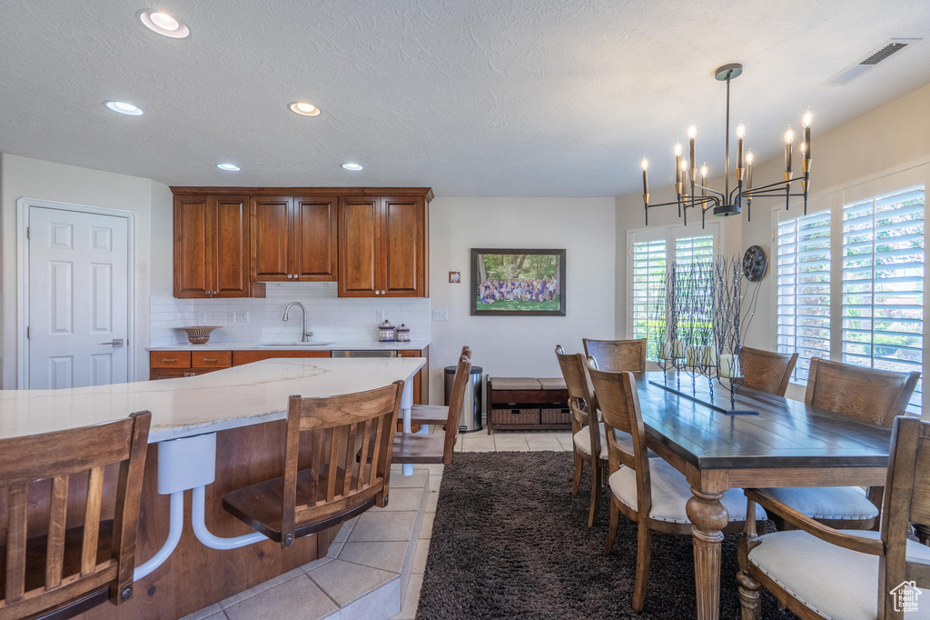 Kitchen with brown cabinetry, recessed lighting, decorative backsplash, a chandelier, and light tile patterned floors