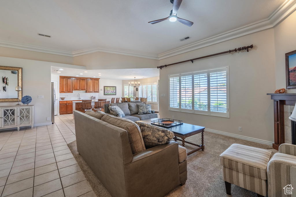 Living room featuring ornamental molding, a chandelier, a ceiling fan, baseboards, and light tile patterned flooring