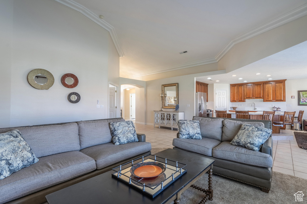 Living area with arched walkways, ornamental molding, light tile patterned floors, and recessed lighting