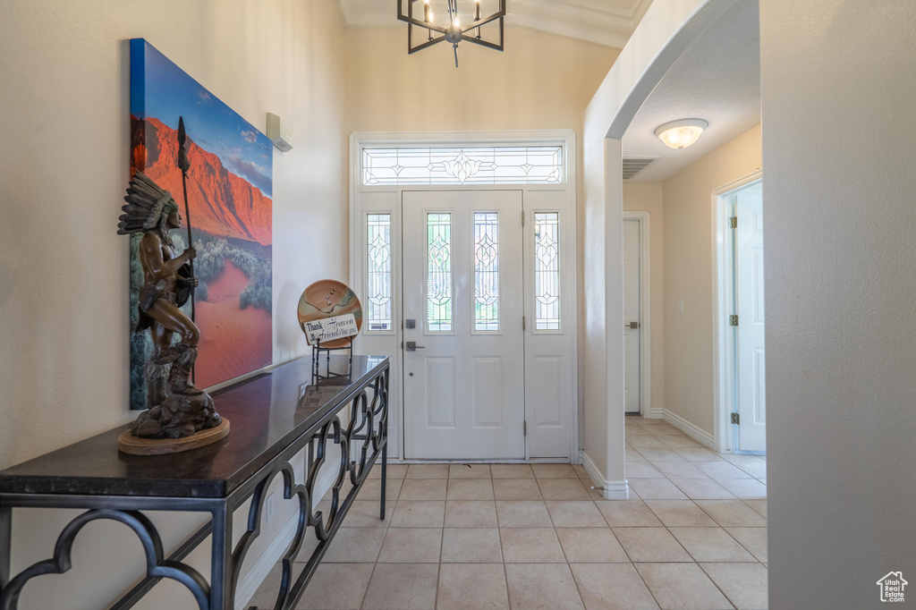 Entryway featuring arched walkways, light tile patterned floors, baseboards, and a chandelier