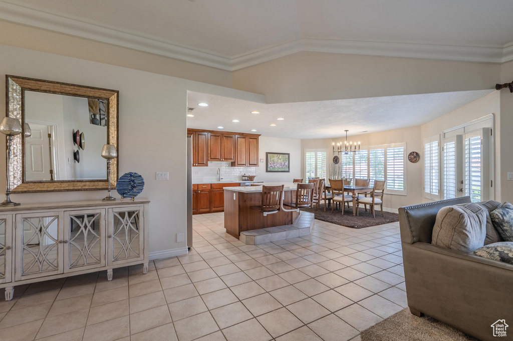 Living area featuring light tile patterned floors, baseboards, a chandelier, recessed lighting, and ornamental molding