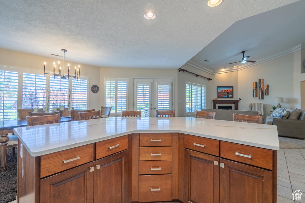 Kitchen with open floor plan, light countertops, ceiling fan, light tile patterned floors, and crown molding