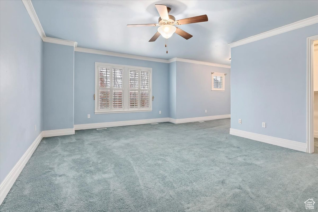 Carpeted empty room featuring ceiling fan and ornamental molding