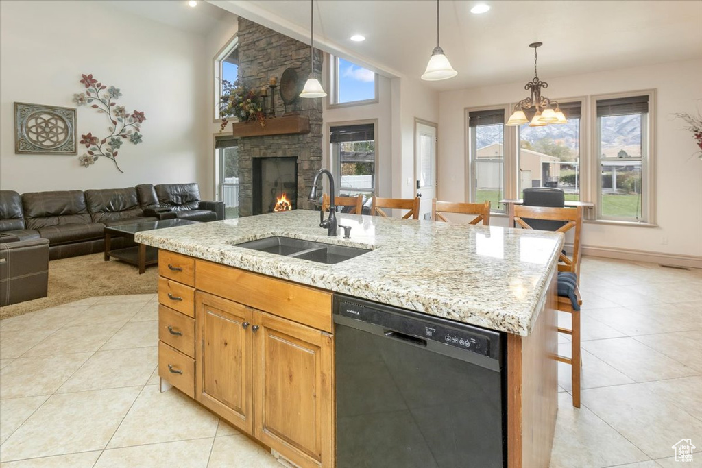 Kitchen featuring a stone fireplace, sink, an island with sink, a kitchen breakfast bar, and dishwasher