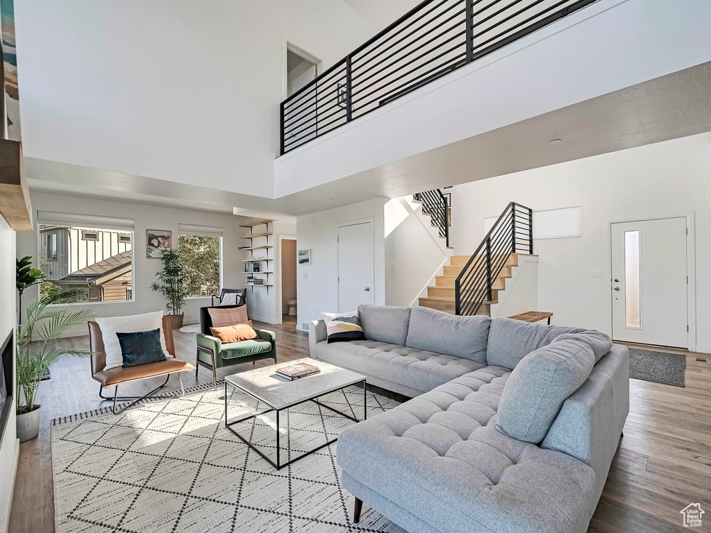 Living area featuring a towering ceiling, wood finished floors, and stairway
