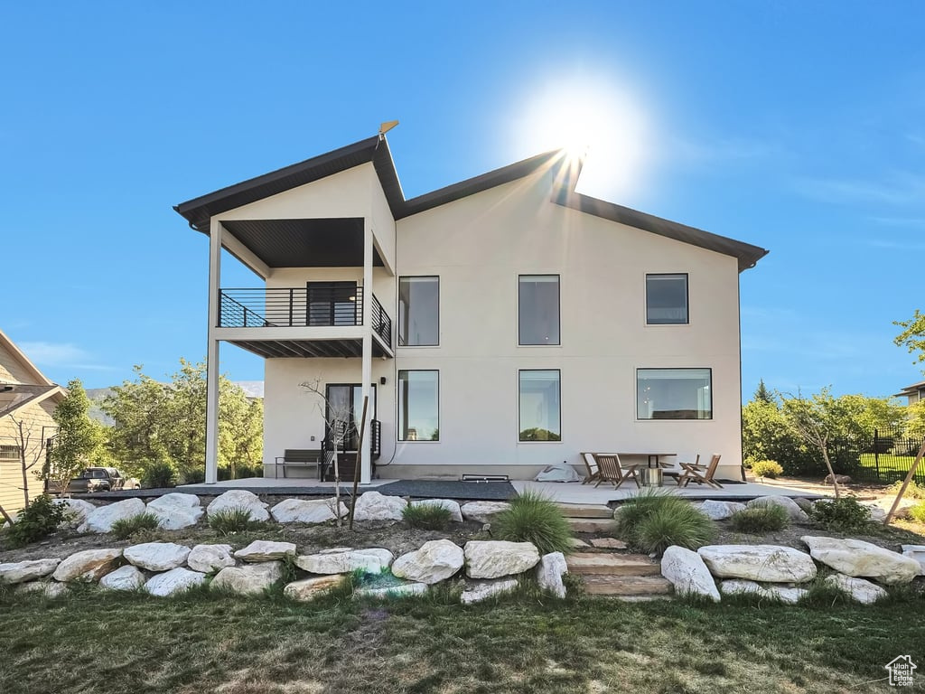 Rear view of property featuring a balcony, stucco siding, and a patio