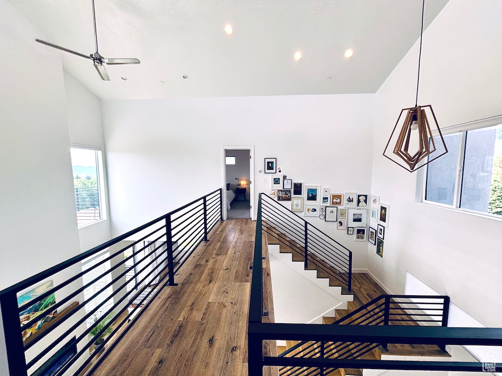 Stairs with wood finished floors, recessed lighting, ceiling fan, and high vaulted ceiling