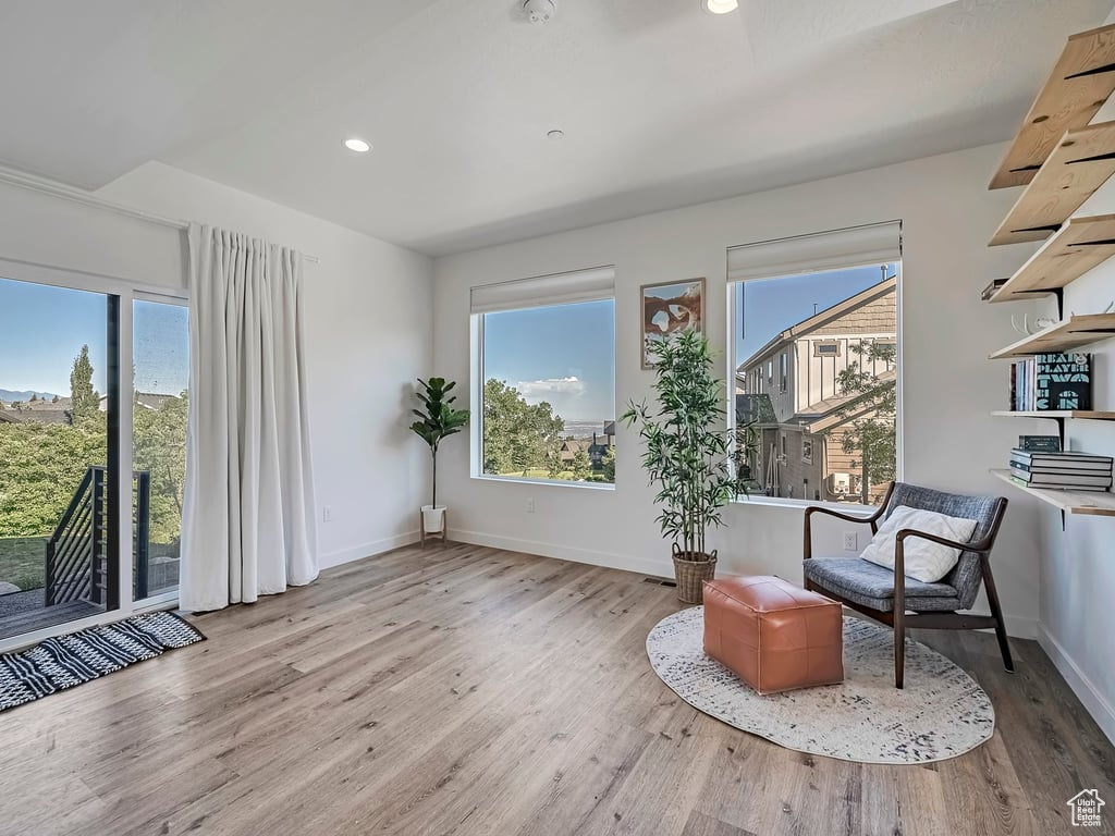 Sitting room with plenty of natural light, wood finished floors, and recessed lighting