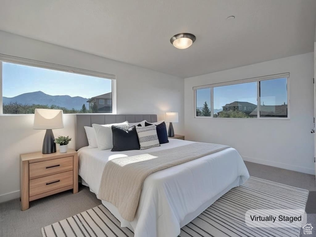 Bedroom with multiple windows, light colored carpet, and a mountain view