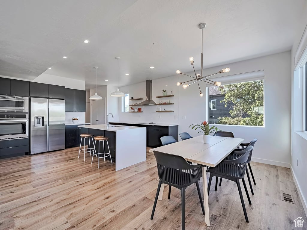 Dining area featuring healthy amount of natural light, a chandelier, light wood finished floors, and recessed lighting
