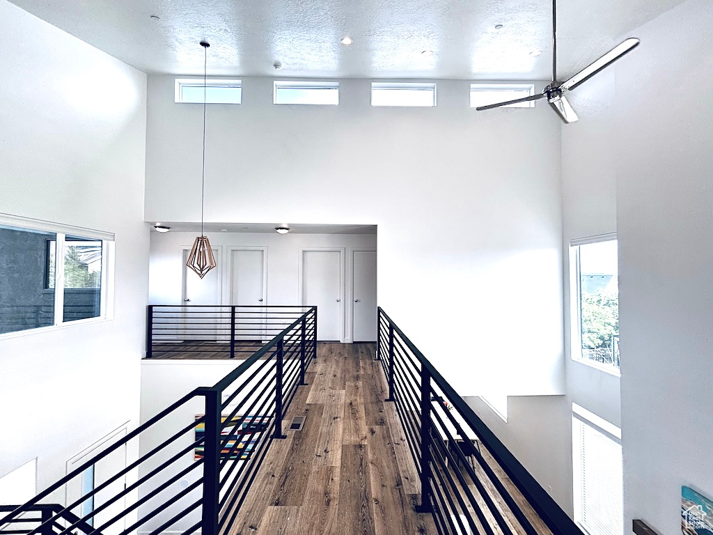 Hallway with a towering ceiling, wood finished floors, and an upstairs landing