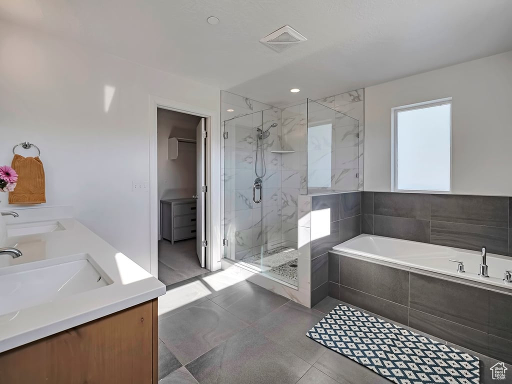 Bathroom with a marble finish shower, a bath, double vanity, and tile patterned floors