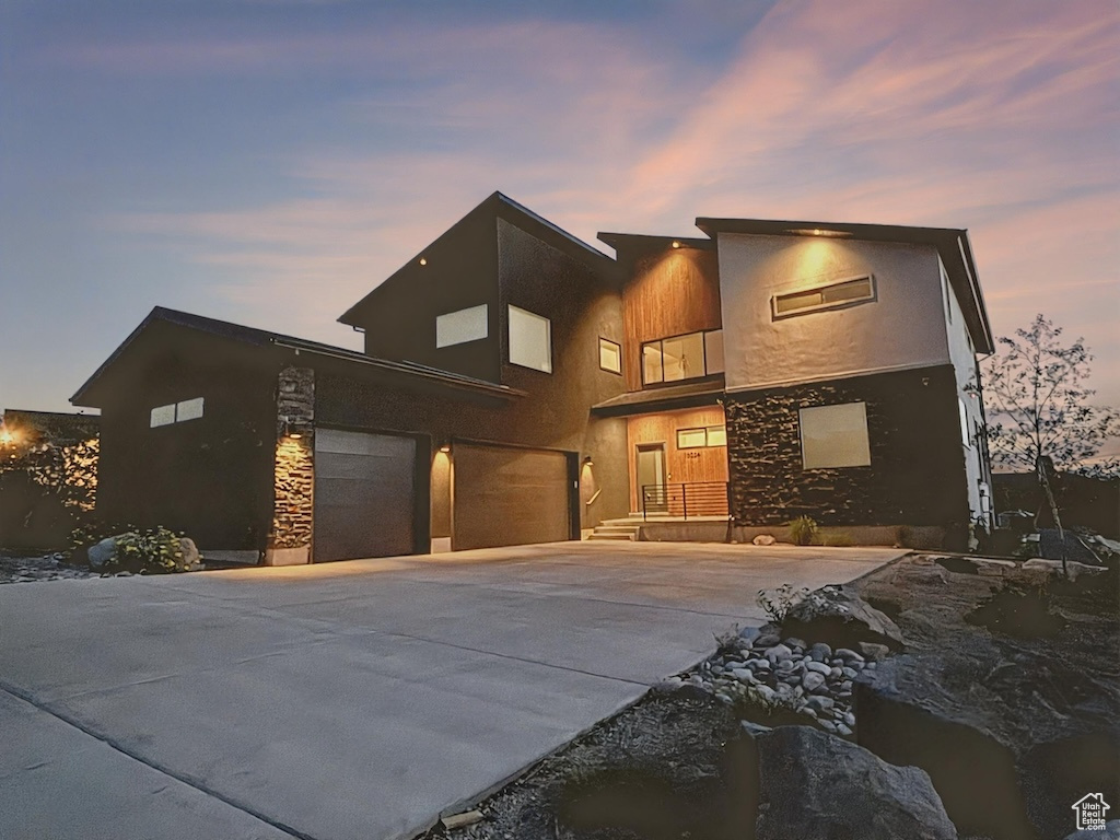 Contemporary home with stone siding, driveway, and a garage