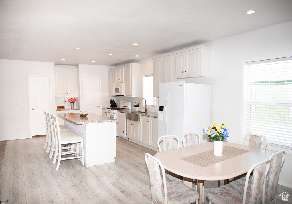 Kitchen featuring light hardwood / wood-style flooring, a kitchen island, white appliances, and white cabinets