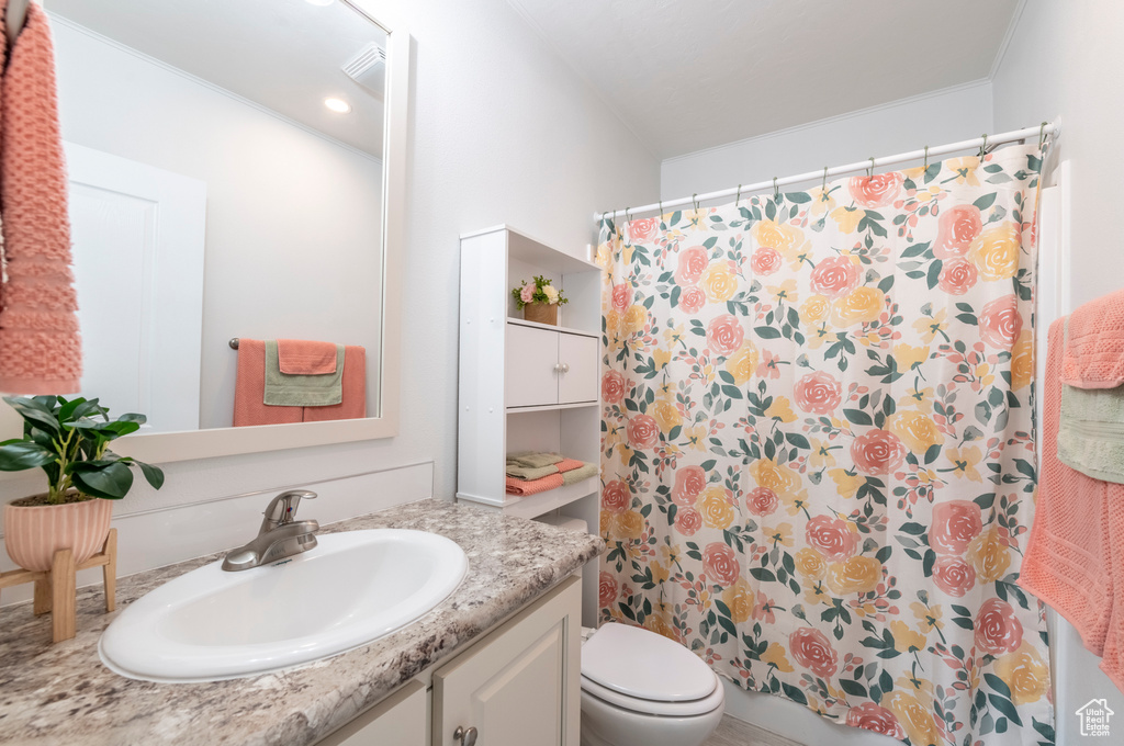 Bathroom with toilet, vanity, a shower with shower curtain, and ornamental molding