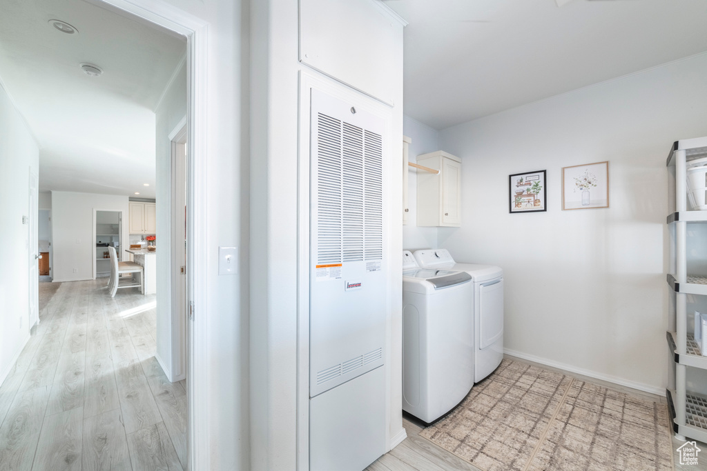 Laundry room with separate washer and dryer, cabinets, and light hardwood / wood-style floors