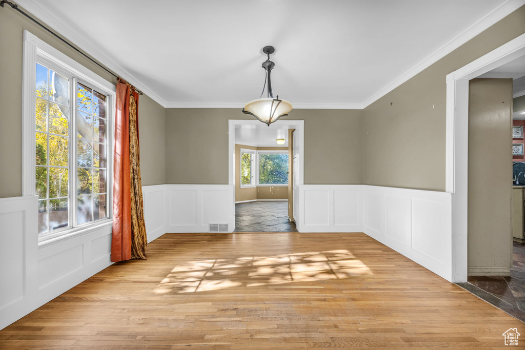 Unfurnished dining area with light hardwood / wood-style floors, a healthy amount of sunlight, and crown molding