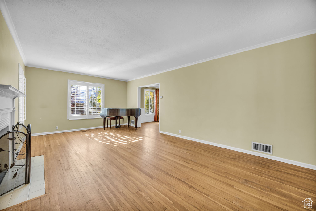 Unfurnished living room featuring light hardwood / wood-style floors and crown molding