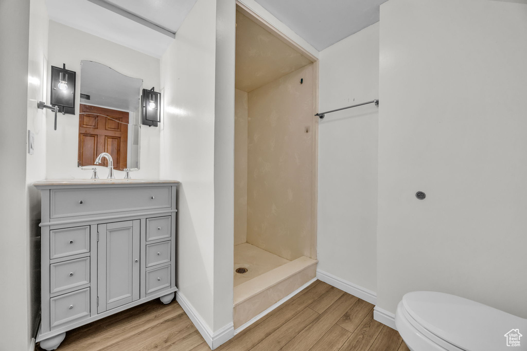 Bathroom with toilet, a shower, vanity, and wood-type flooring