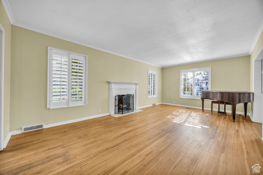 Unfurnished living room featuring light hardwood / wood-style flooring and crown molding