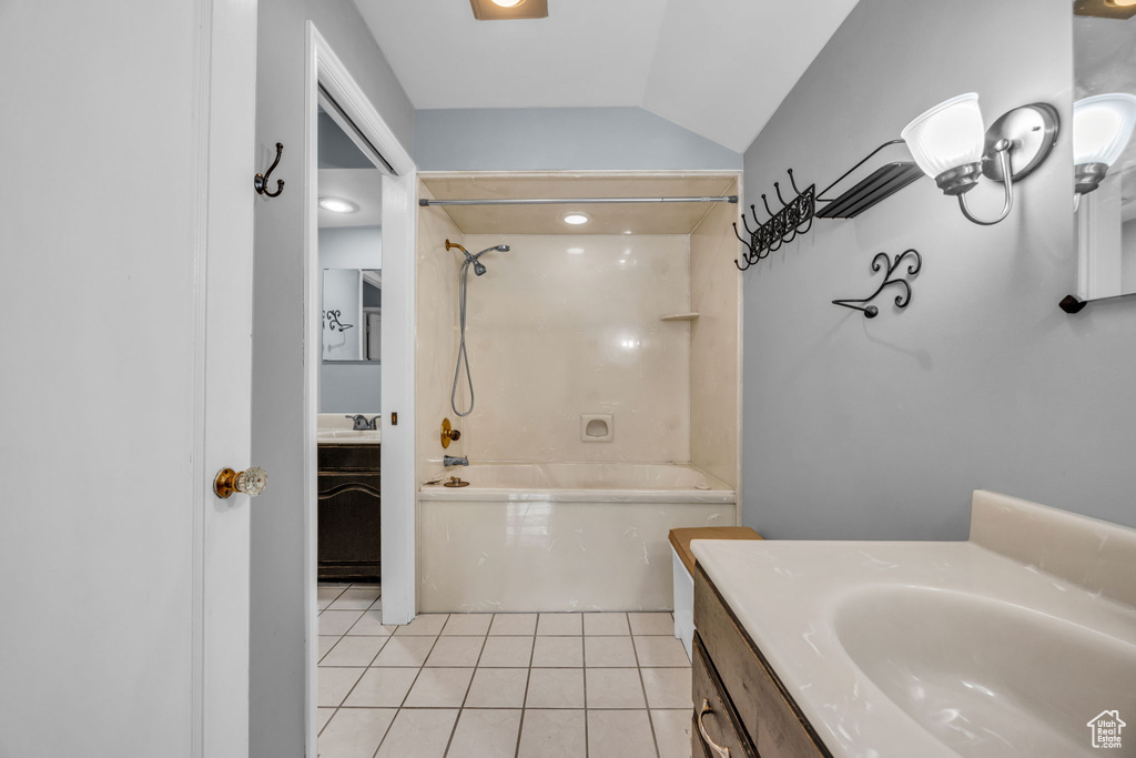 Bathroom with vanity, tile patterned floors, tiled shower / bath, and vaulted ceiling