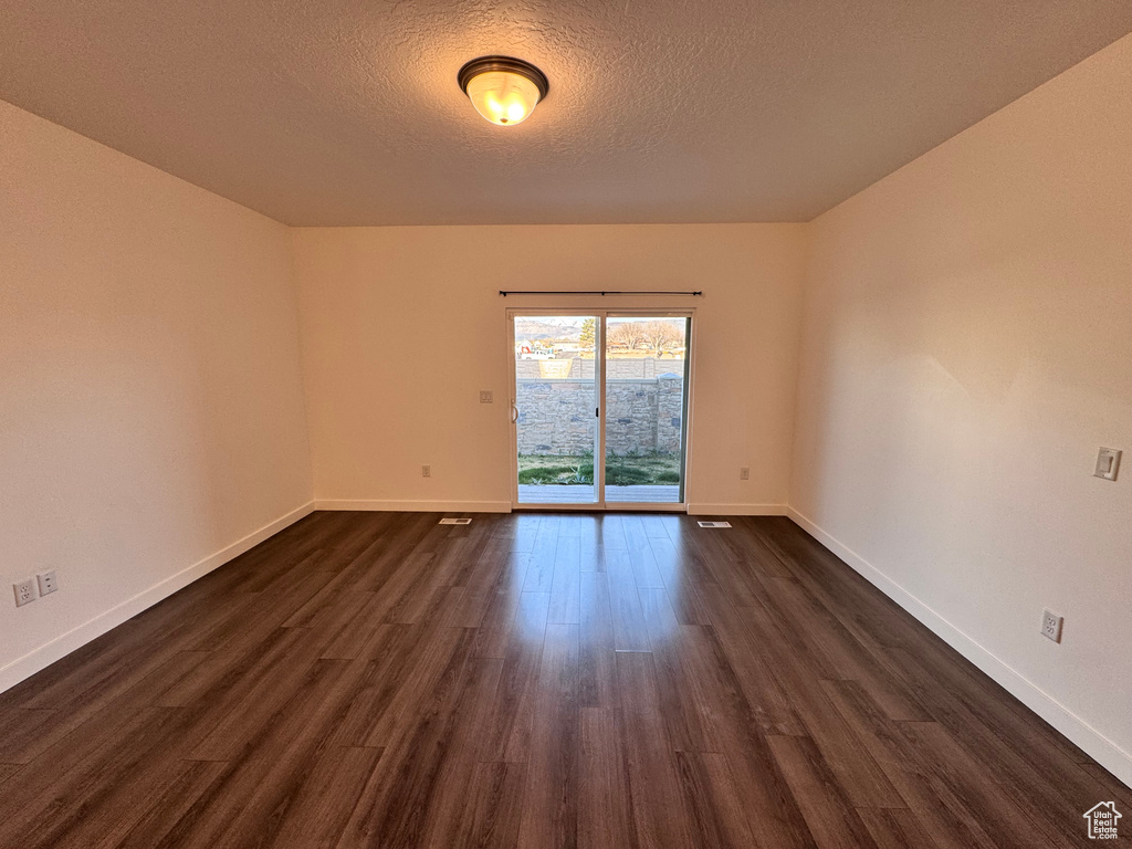 Empty room with dark wood-style floors, baseboards, and a textured ceiling