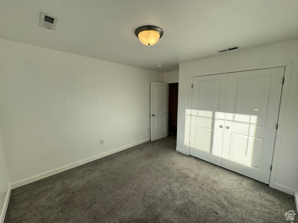 Unfurnished bedroom featuring baseboards, visible vents, carpet floors, and a textured ceiling