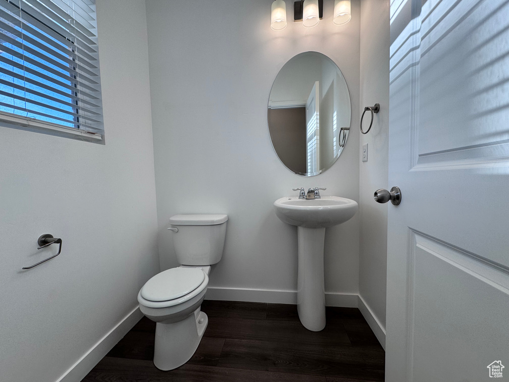 Half bath featuring baseboards, toilet, a sink, and wood finished floors