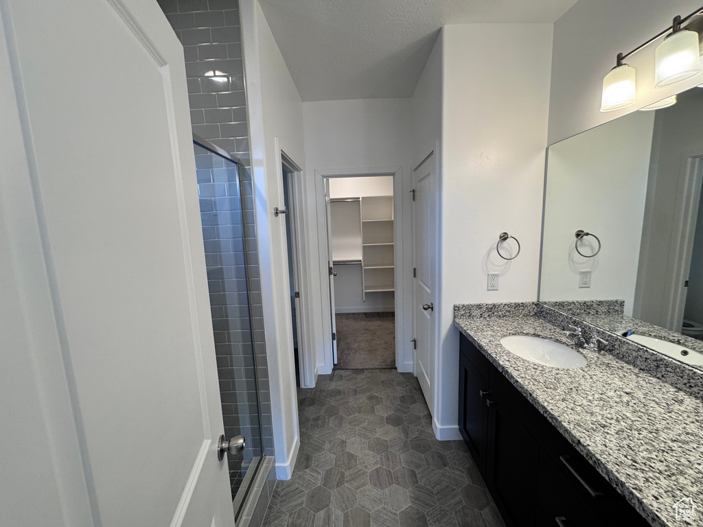 Bathroom with a shower stall, baseboards, a spacious closet, and vanity