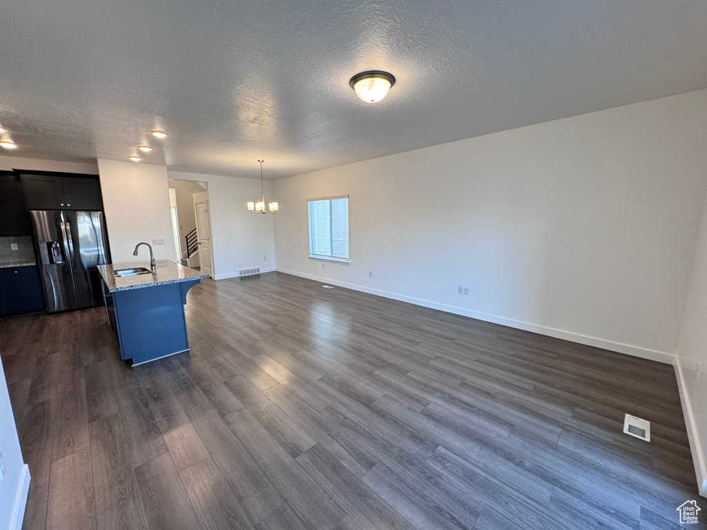 Kitchen with a kitchen bar, refrigerator with ice dispenser, dark wood finished floors, a sink, and a notable chandelier