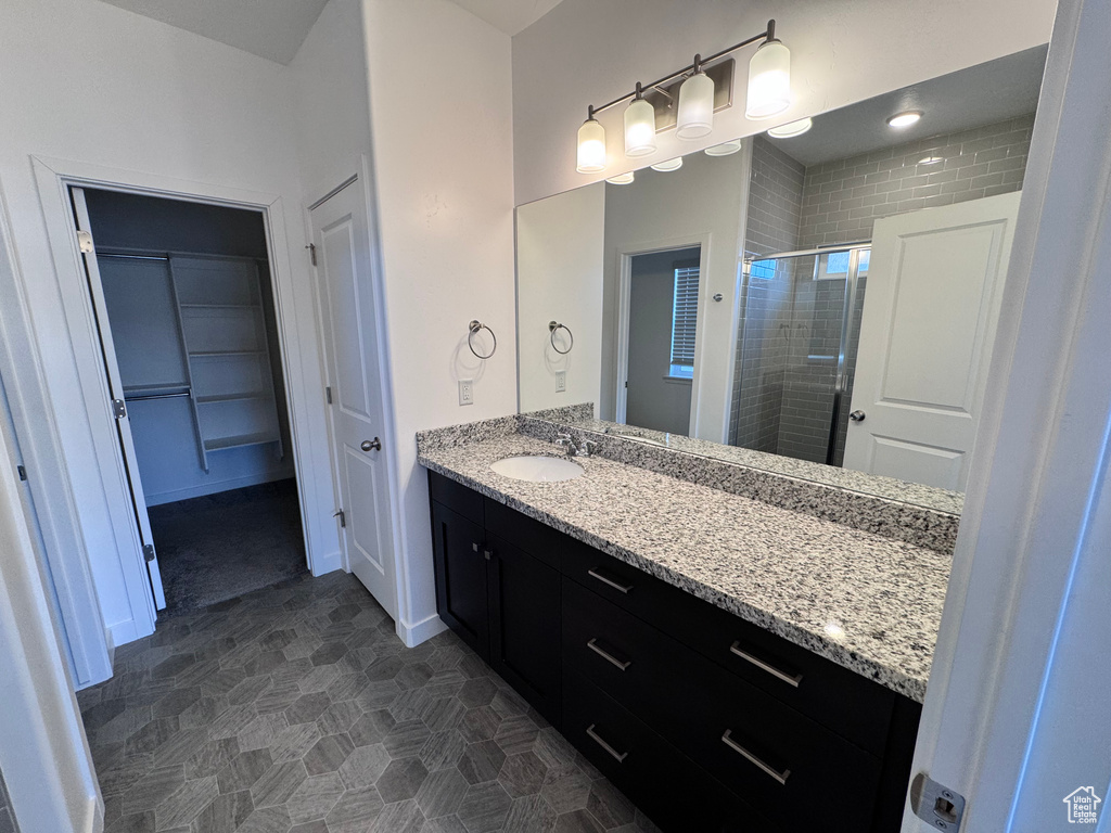 Bathroom featuring baseboards, a stall shower, a walk in closet, and vanity